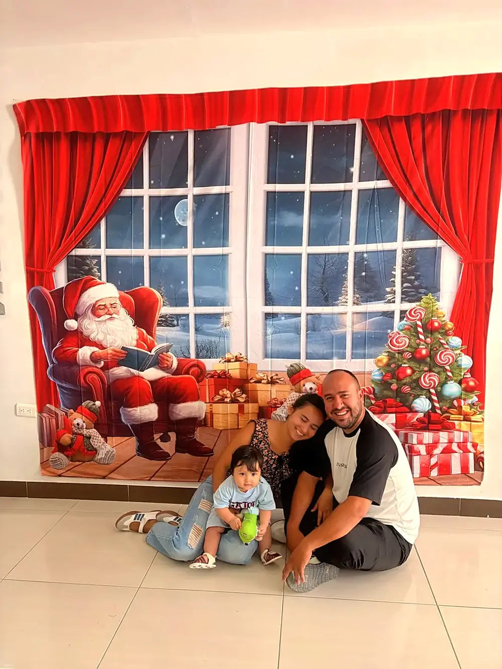 Familia sentada frente al telón navideño Leyendo instalado en una pared